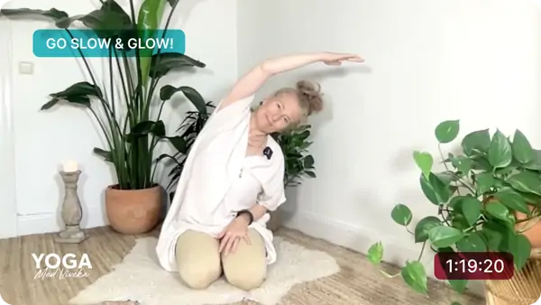 Viveka leder en yoga class med mjuka sträckningar, omgiven av gröna växter i en lugn och harmonisk atmosfär.
