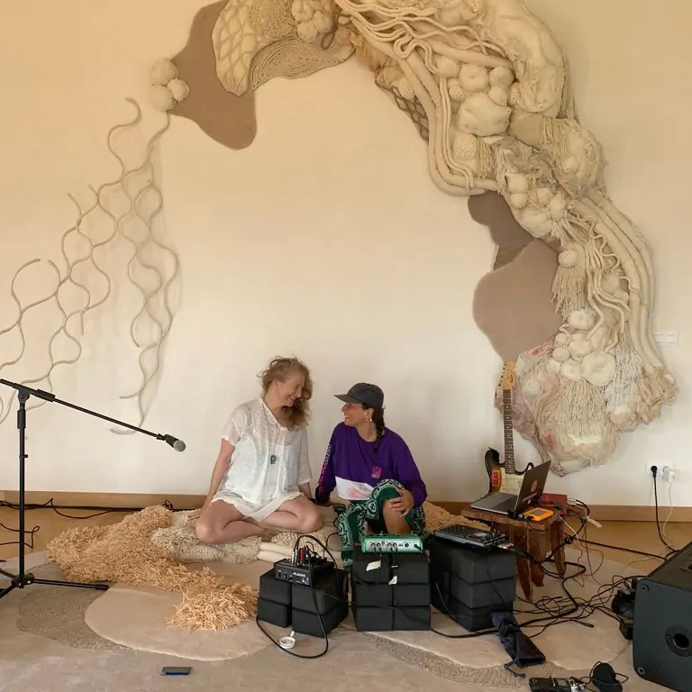 Viveka och Djile skapar magi under Kundalini Rave, omgivna av en unik väggkonst och ljudutrustning.